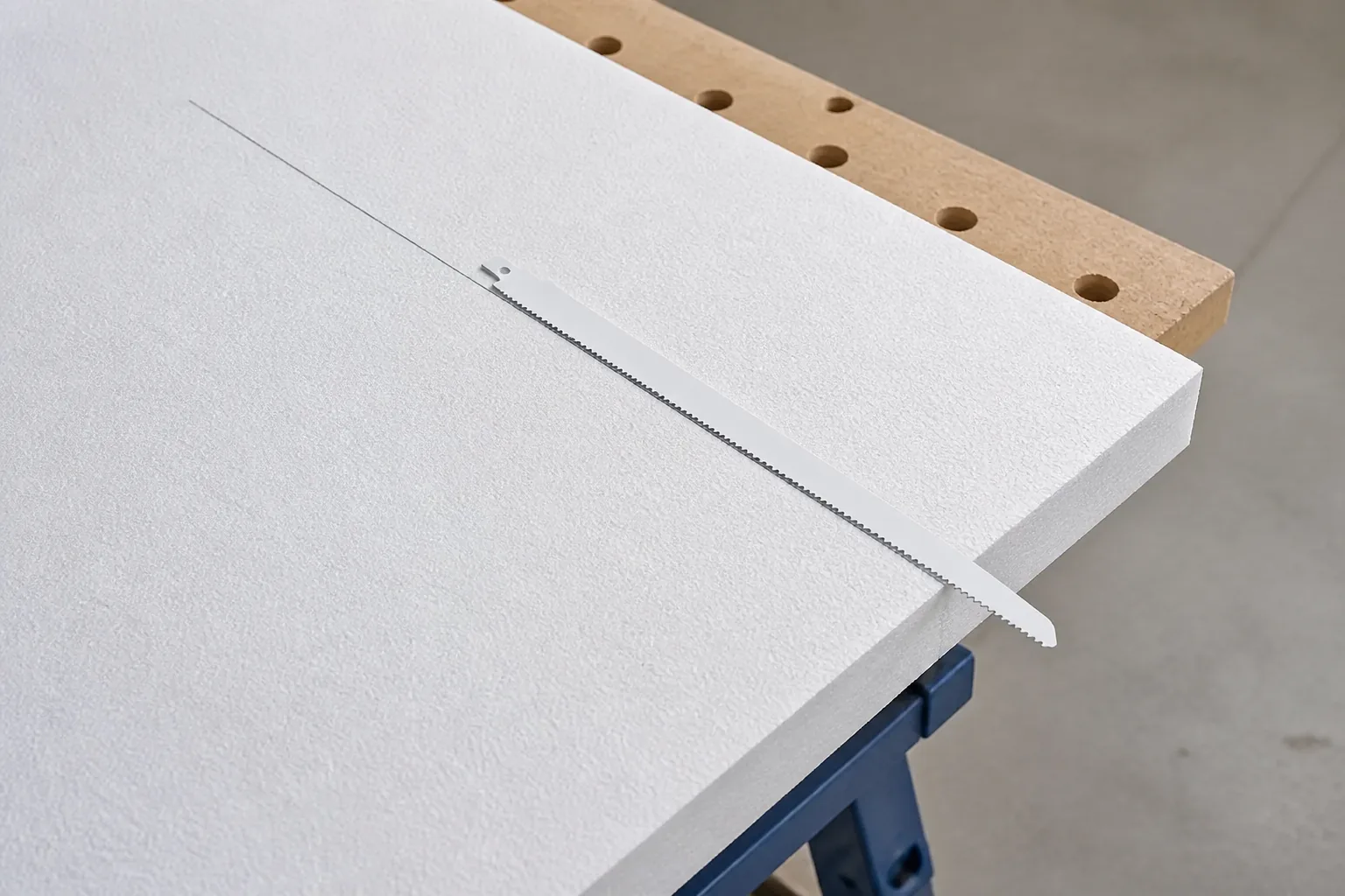 Rigid foam board marked for cutting beside a long reciprocating blade